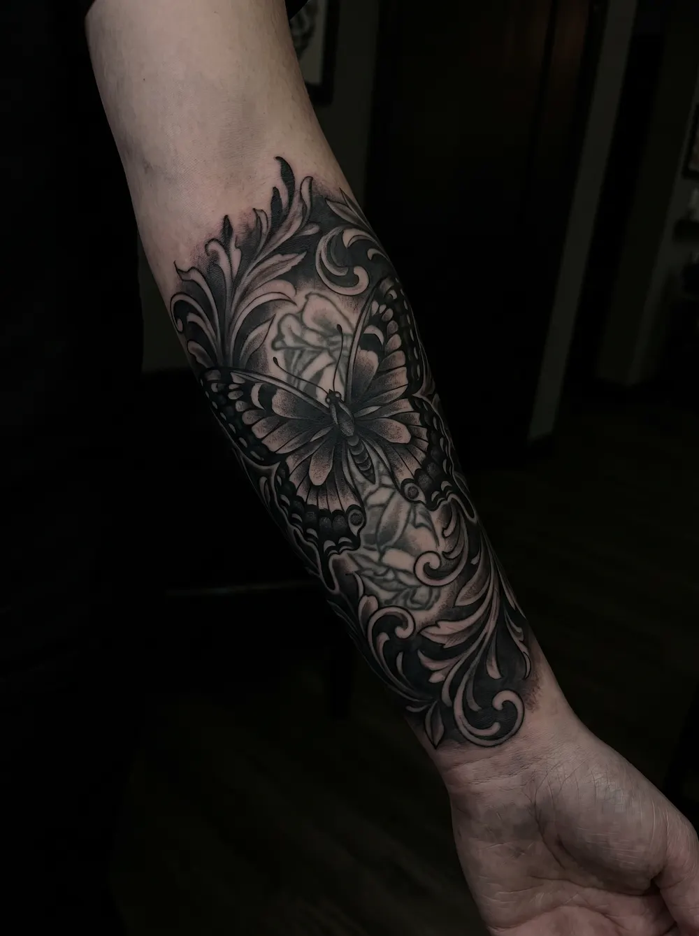 Ornate butterfly cover-up, wings dense with pattern and shadow, on the forearm